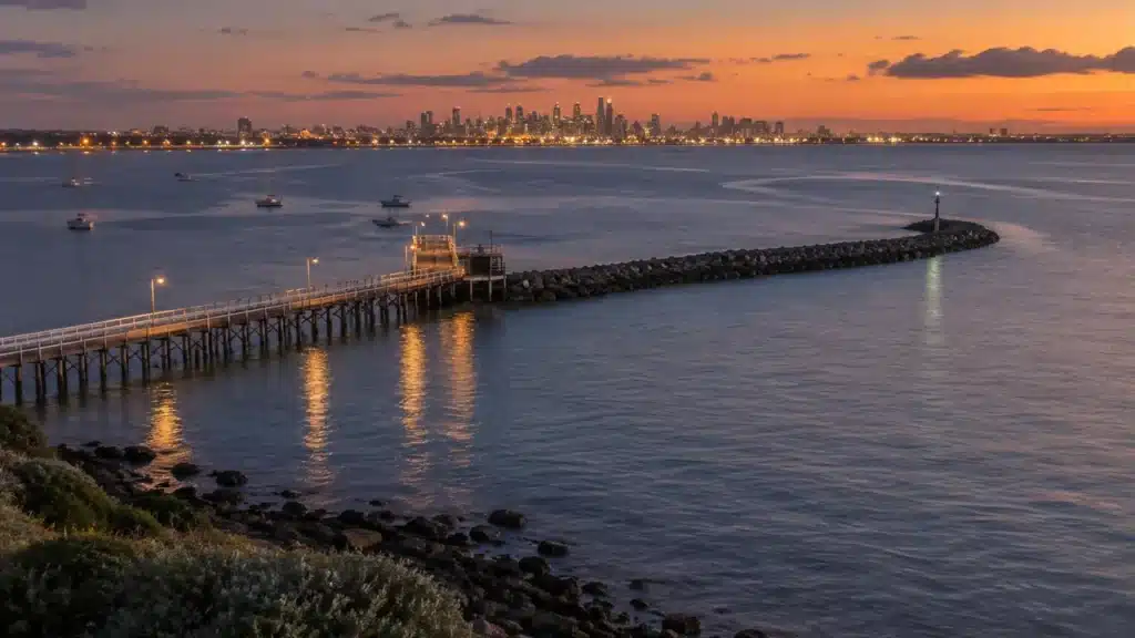 Aerial view of a pier and curving rock breakwater at dusk